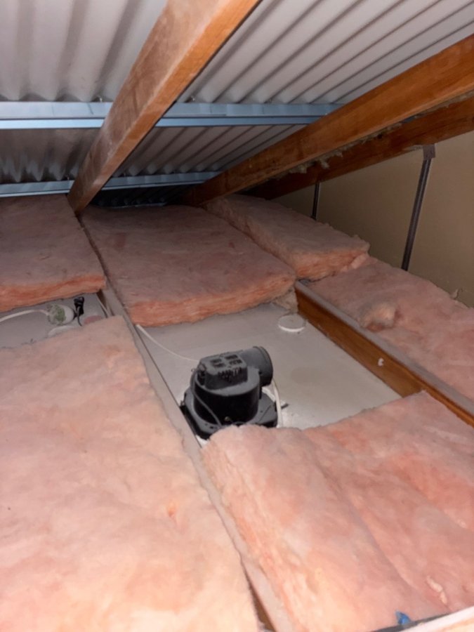 Roof space above a Pimpama ensuite showing insulation batts displaced either side of the exhaust fan housing