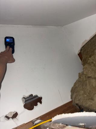 Moisture meter being used on the concealed face of a ceiling lining inside a cavity