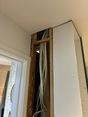 Opened bulkhead above a doorway exposing timber framing and electrical services